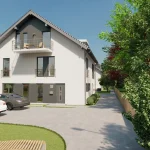 Das Bild zeigt eine moderne Wohnanlage mit zwei weißen Mehrfamilienhäusern, die beide graue Dächer und Balkone haben. Es sind zwei Autos geparkt und der Bereich ist von grünen Bäumen und Sträuchern umgeben. Der Standort könnte in der Nähe des Ammersees sein, wie das Projekt "Buch a. Ammersee" nahelegt.