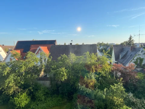 Ausblick über eine begrünte Wohnsiedlung mit Einfamilienhäusern bei strahlendem Sonnenschein
