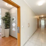 Blick durch die Eingangstür in den Flur einer gepflegten Wohnung mit hellen Fliesen, Einbauschrank und Blick ins lichtdurchflutete Wohnzimmer