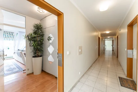 Blick durch die Eingangstür in den Flur einer gepflegten Wohnung mit hellen Fliesen, Einbauschrank und Blick ins lichtdurchflutete Wohnzimmer