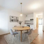 Einrichtungsbeispiel eines modernen Essbereichs in einer Wohnung nahe dem Englischen Garten, mit Holztisch und hellen Stühlen.