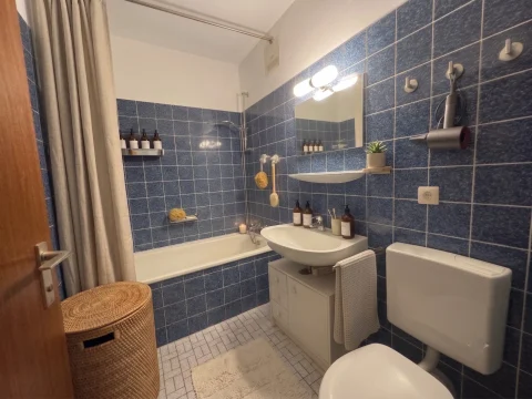 innenliegendes Badezimmer mit blauen Fliesen, weißer Keramik und geschmackvollen neuen Accessoires.