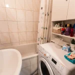 Badezimmer mit Badewanne, Waschbecken und integrierter Waschmaschine