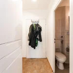Blick auf den Flur und das Badezimmer einer Wohnung mit heller Wandfarbe