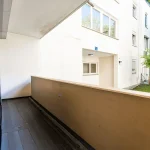 Blick von der Loggia einer modernen Wohnung ins Grüne mit Blick auf die weiße Hausfassade
